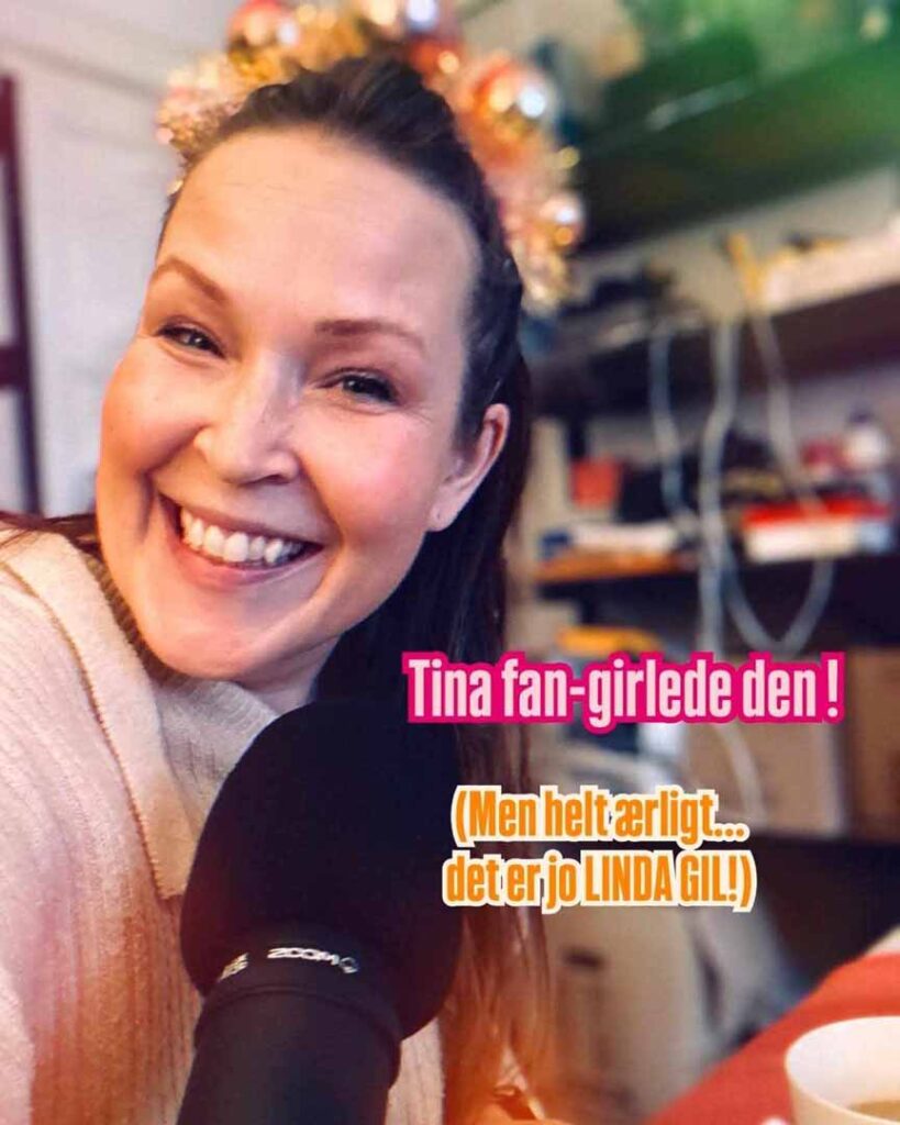 Foto af en smilende kvinde med festlig, lyserød hovedbeklædning med glitter og en mikrofon